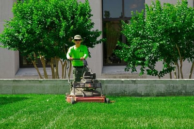 Level Green Landscaping technician mowing grass