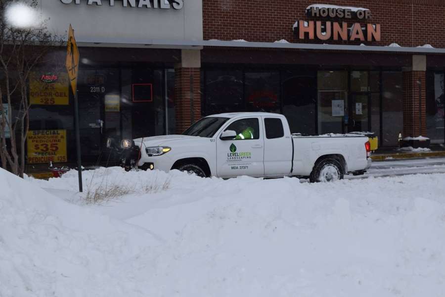 truck and snow plow move snow at commercial building