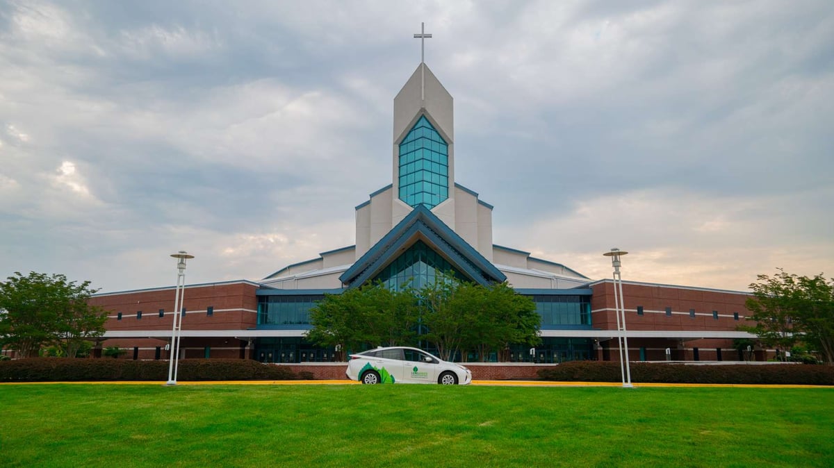 church with nice landscaping and level green car parked out front