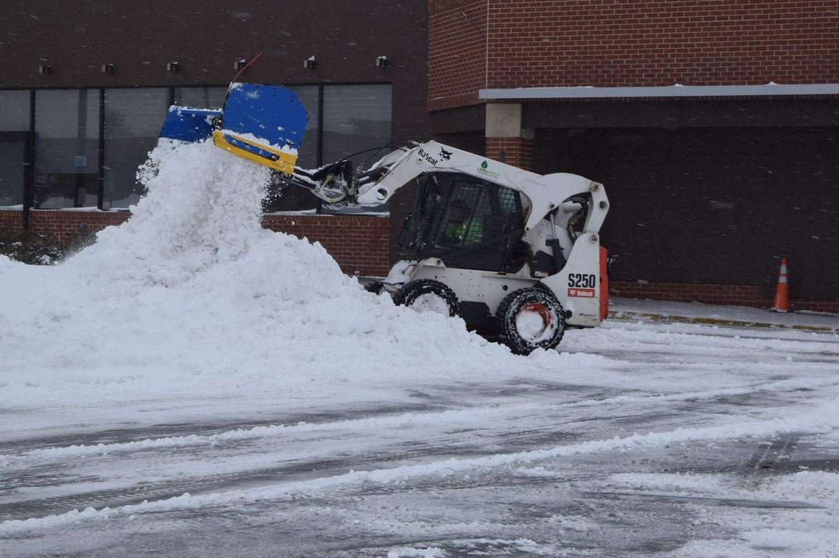 skid steer piles snow in parking lot