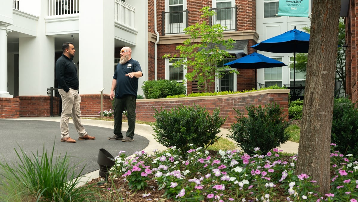 account manager and property manager meet near flowers and plantings in driveway