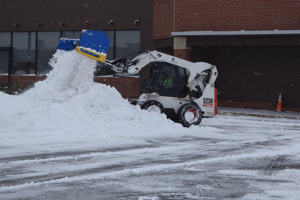 skid loader moves snow in pile